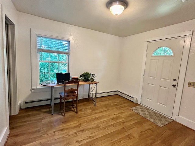 office space featuring a wealth of natural light, a baseboard heating unit, and hardwood / wood-style flooring