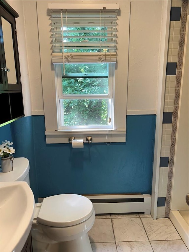 bathroom featuring toilet, sink, a tile shower, and a baseboard radiator