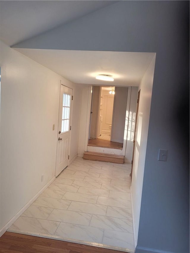 corridor featuring marble finish floor and baseboards