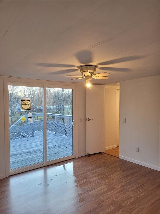 unfurnished room with wood finished floors, a ceiling fan, and baseboards