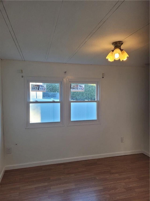 empty room featuring baseboards and dark wood-style flooring