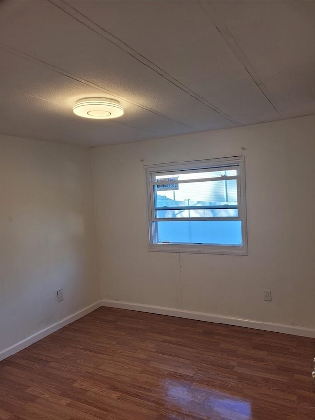 empty room featuring a textured ceiling, baseboards, and wood finished floors