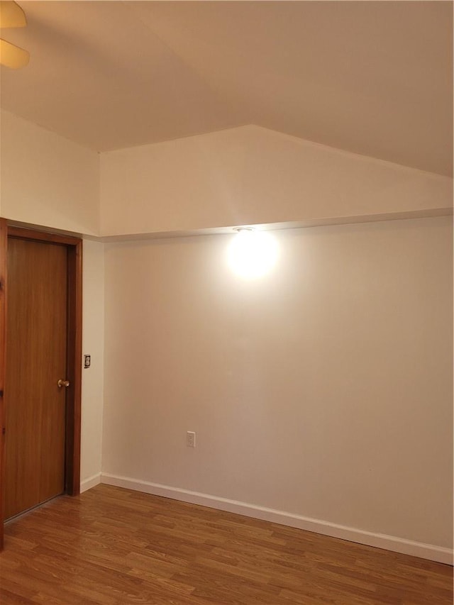 unfurnished room featuring baseboards, vaulted ceiling, and wood finished floors