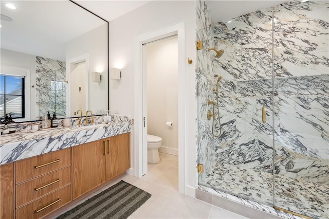 bathroom with tile patterned floors, vanity, a shower with shower door, and toilet