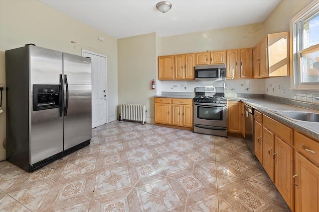 kitchen featuring stainless steel appliances, sink, radiator heating unit, and decorative backsplash