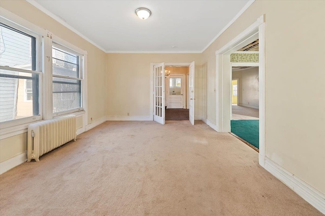 empty room featuring crown molding, radiator heating unit, light colored carpet, and french doors