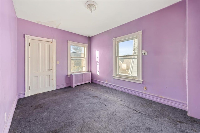 carpeted empty room featuring radiator heating unit