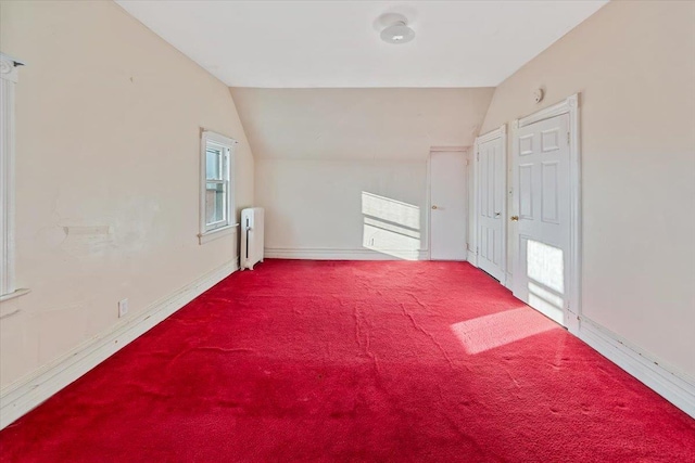 bonus room with vaulted ceiling, radiator, and carpet flooring