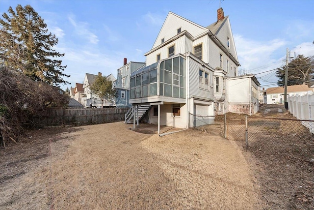 rear view of house featuring a garage and a sunroom