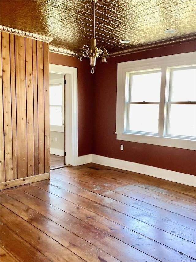 unfurnished dining area with a wealth of natural light, a notable chandelier, and hardwood / wood-style flooring