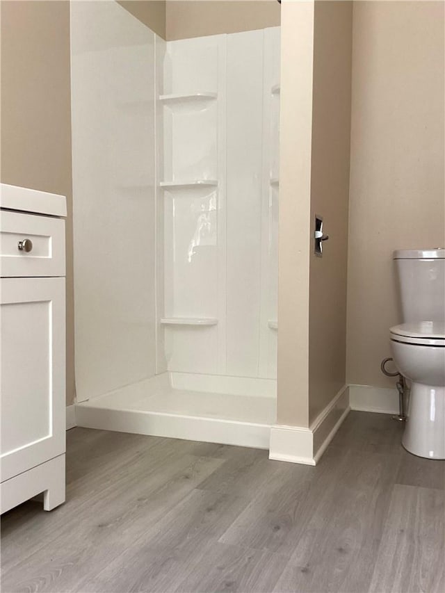 bathroom featuring walk in shower, hardwood / wood-style floors, and toilet