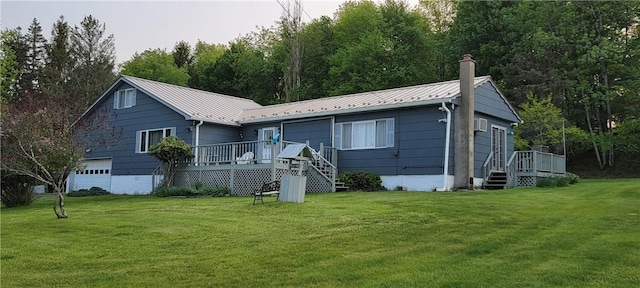 back of property with a garage, a yard, and a wooden deck