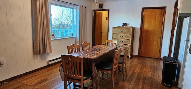 dining space featuring ornamental molding, dark hardwood / wood-style flooring, a baseboard heating unit, and wood walls