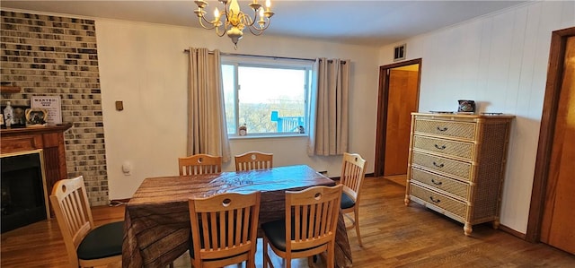 dining space featuring a fireplace, dark hardwood / wood-style flooring, a chandelier, and ornamental molding