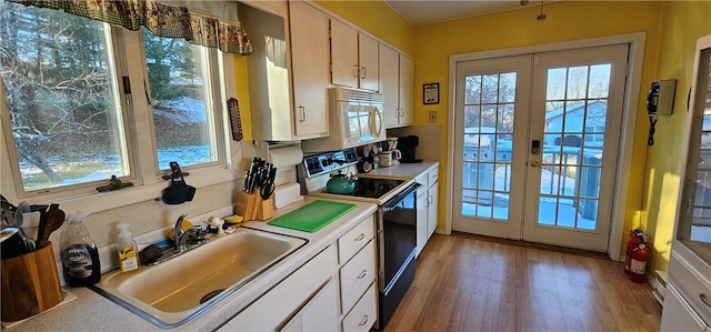 kitchen with french doors, light wood-type flooring, black range with electric cooktop, sink, and white cabinetry