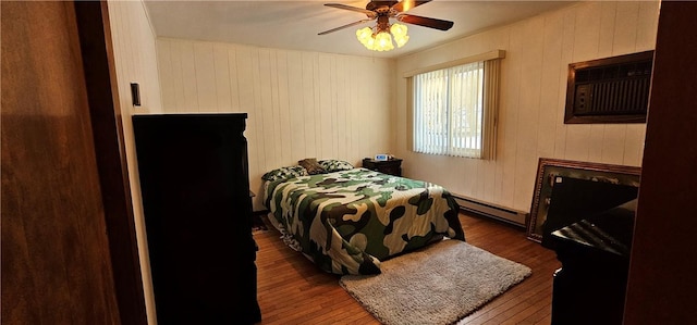 bedroom featuring dark hardwood / wood-style flooring, a wall unit AC, ceiling fan, a baseboard heating unit, and wood walls