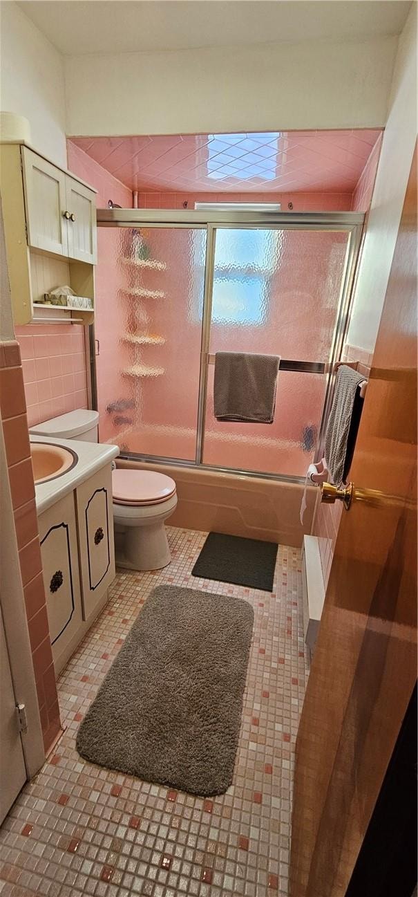 full bathroom featuring tasteful backsplash, tile patterned floors, vanity, shower / bath combination with glass door, and toilet