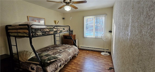 bedroom with dark hardwood / wood-style floors, ceiling fan, and a baseboard heating unit