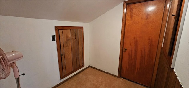 hall with lofted ceiling and light carpet