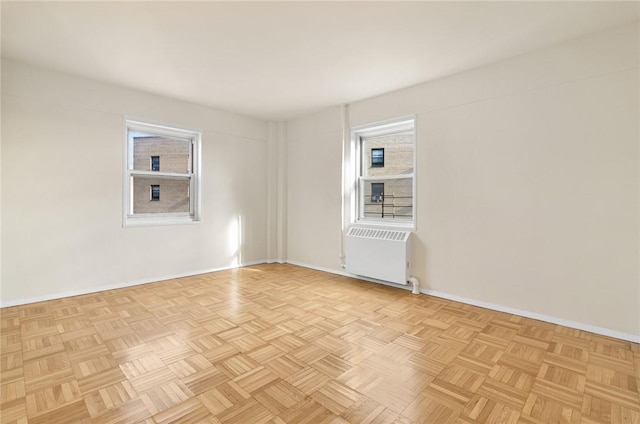 unfurnished room featuring radiator heating unit, light parquet flooring, and a wealth of natural light