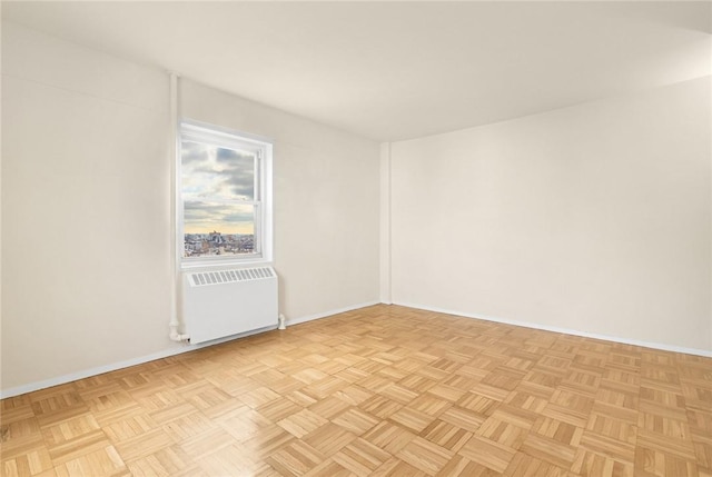 empty room featuring radiator heating unit and light parquet flooring