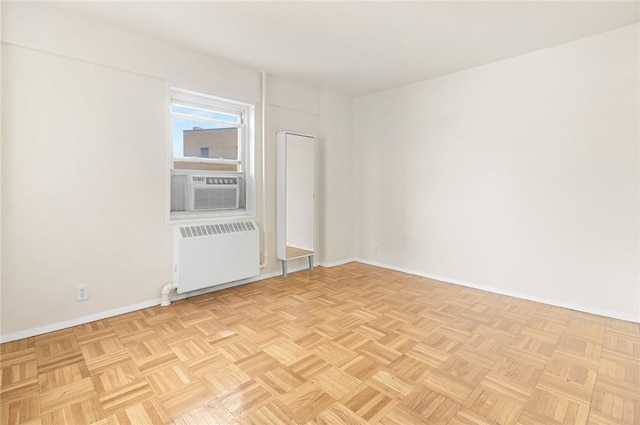 empty room featuring radiator heating unit, light parquet flooring, and cooling unit