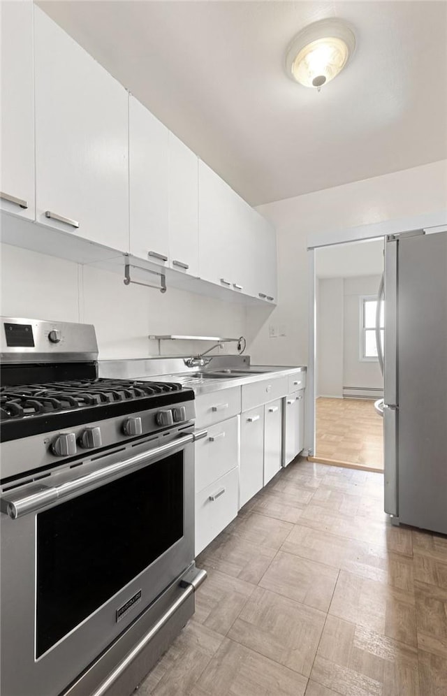 kitchen with white cabinets, stainless steel appliances, baseboard heating, and sink