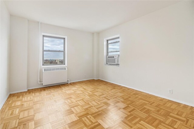 empty room featuring cooling unit, radiator, and light parquet flooring