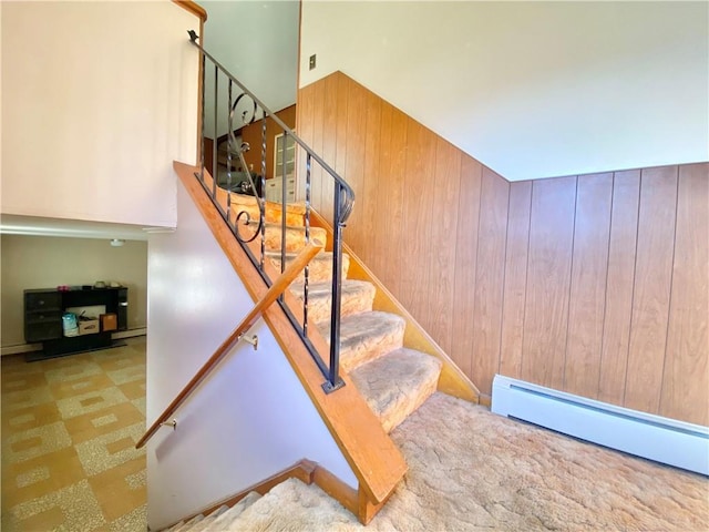 stairway featuring wood walls and a baseboard radiator