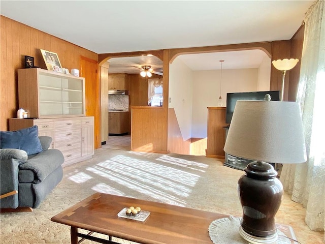 living room with light carpet, ceiling fan, and wooden walls