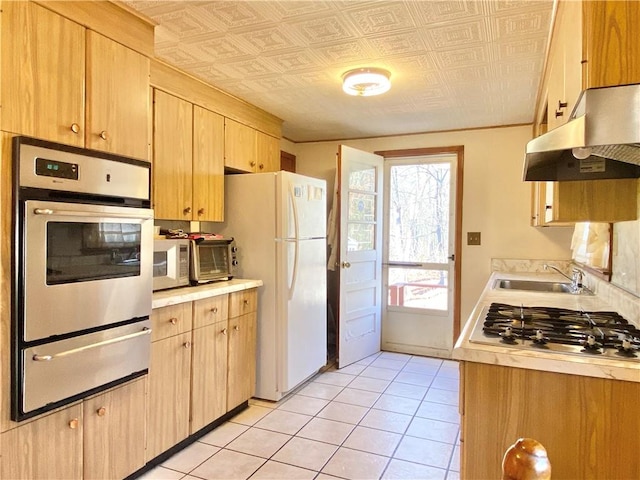 kitchen featuring light tile patterned flooring, appliances with stainless steel finishes, light brown cabinetry, and sink