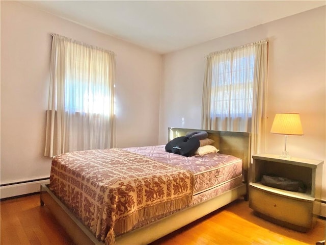 bedroom with wood-type flooring and a baseboard radiator