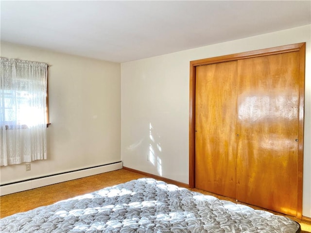 unfurnished bedroom featuring baseboard heating and a closet