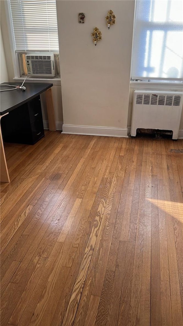 unfurnished dining area featuring radiator heating unit, cooling unit, and light wood-type flooring