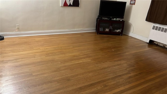 unfurnished living room with radiator heating unit and wood-type flooring