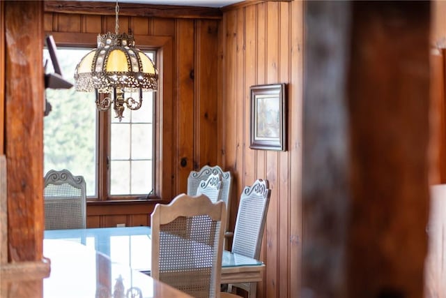 dining space with wood walls and a chandelier