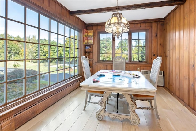 dining space featuring beam ceiling, wood walls, light hardwood / wood-style floors, and a notable chandelier