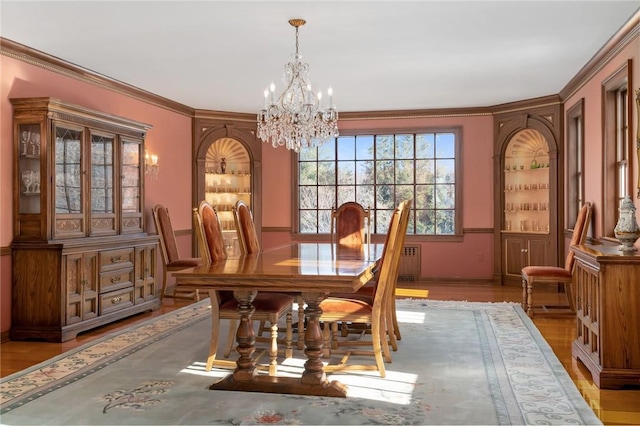 dining area with a chandelier, light wood-type flooring, and crown molding