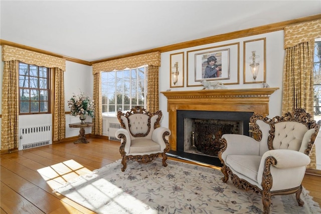 sitting room featuring hardwood / wood-style floors, radiator heating unit, and ornamental molding