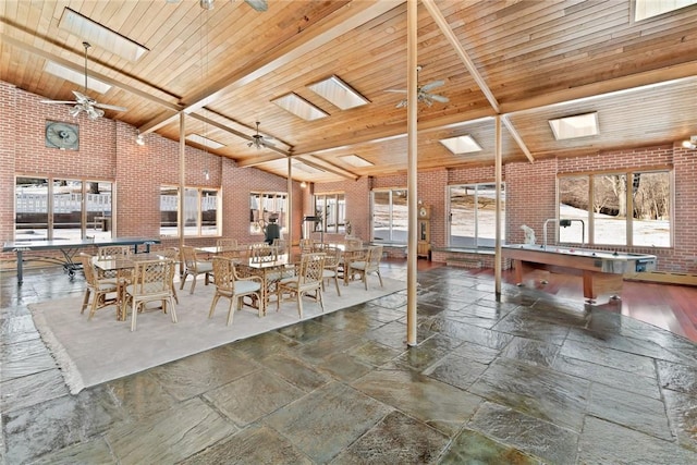 unfurnished dining area with high vaulted ceiling, billiards, ceiling fan, beamed ceiling, and brick wall