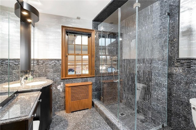 bathroom featuring a shower with door, vanity, and tile walls