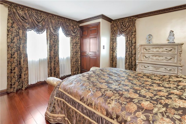 bedroom with multiple windows, a closet, dark hardwood / wood-style floors, and ornamental molding