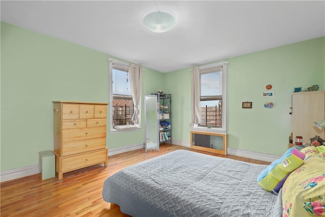 bedroom featuring hardwood / wood-style floors, radiator heating unit, and multiple windows