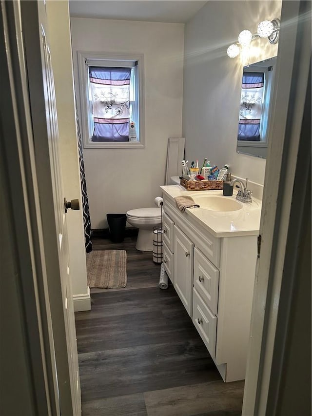 bathroom with toilet, wood finished floors, and vanity