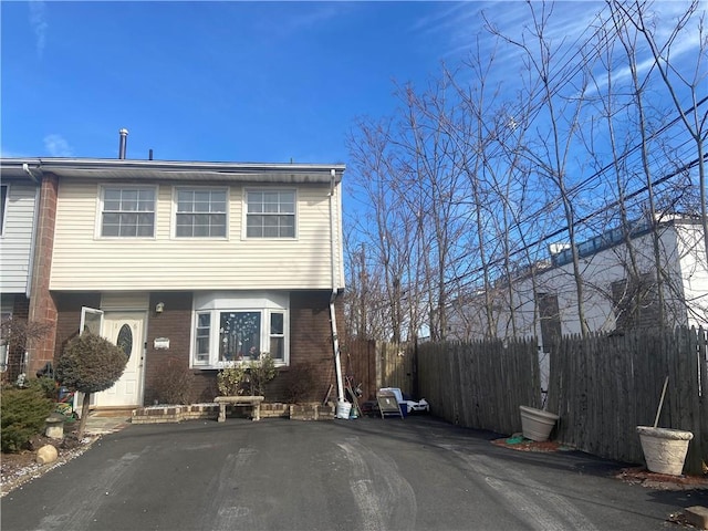 view of front of house with brick siding, fence, and driveway