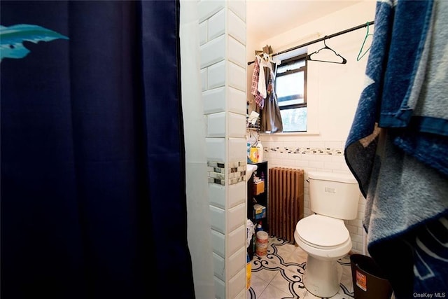 bathroom with radiator heating unit, tile patterned flooring, tile walls, and toilet