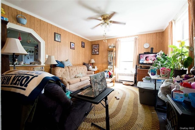 living room with radiator, ceiling fan, wooden walls, and ornamental molding