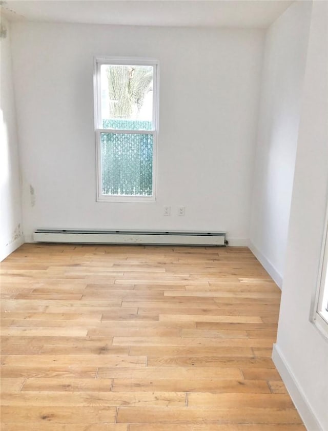 spare room with baseboard heating and light hardwood / wood-style flooring