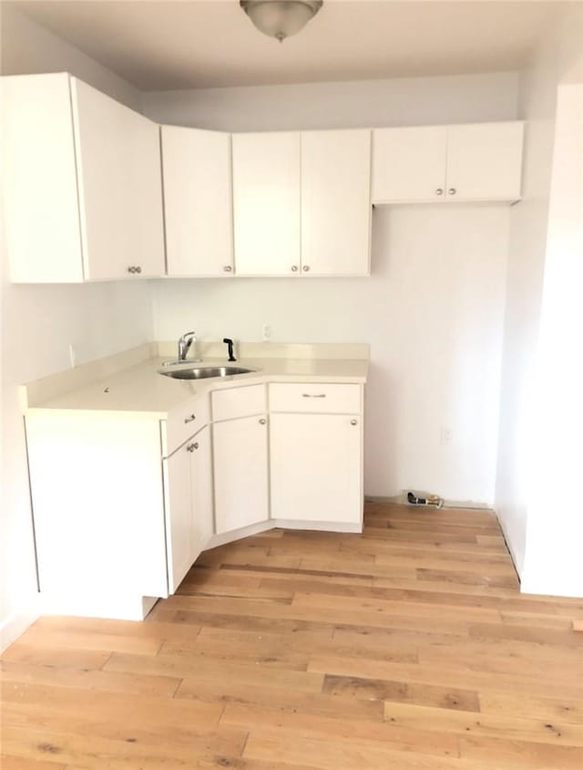 kitchen featuring light hardwood / wood-style floors, white cabinetry, and sink