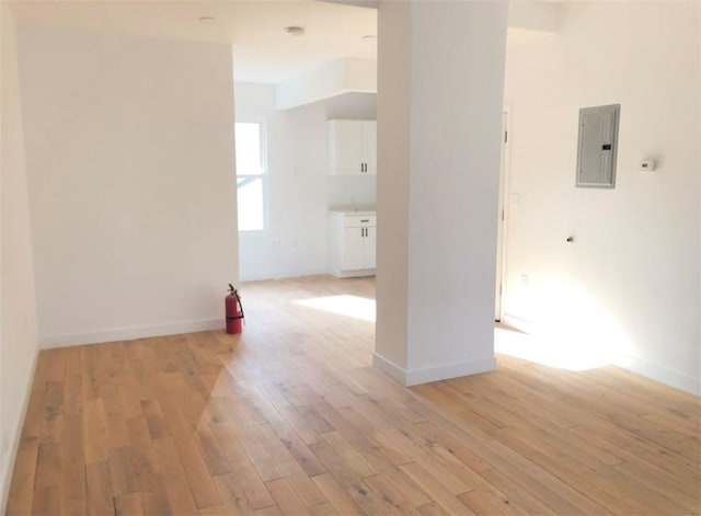 spare room with electric panel and light hardwood / wood-style flooring